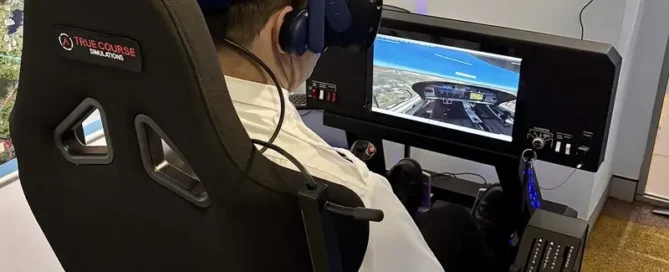 Student pilot using a VR flight simulator with yoke, throttle, and headset while watching a cockpit view on a screen.